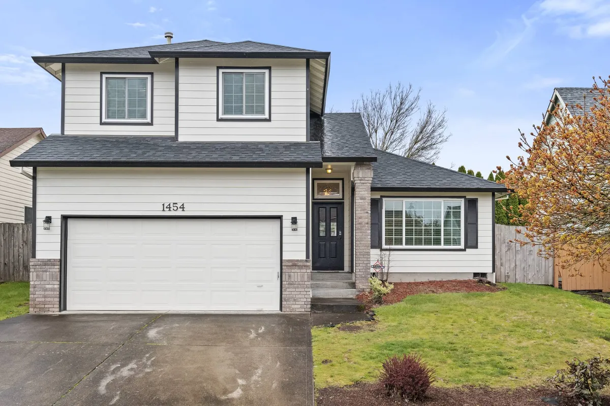 A cheerful exterior view of the home, showing the front door, garage, and a landscaped yard. The scene suggests a welcoming entry point and hints at the comfort and togetherness families and friends can experience here.