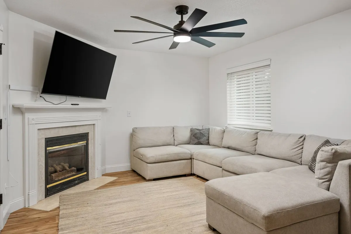 A spacious sectional couch anchors the living room, complemented by a cozy fireplace and a wall-mounted television. The arrangement invites relaxation and group conversation, making it the perfect hub for unwinding or enjoying a movie night together.