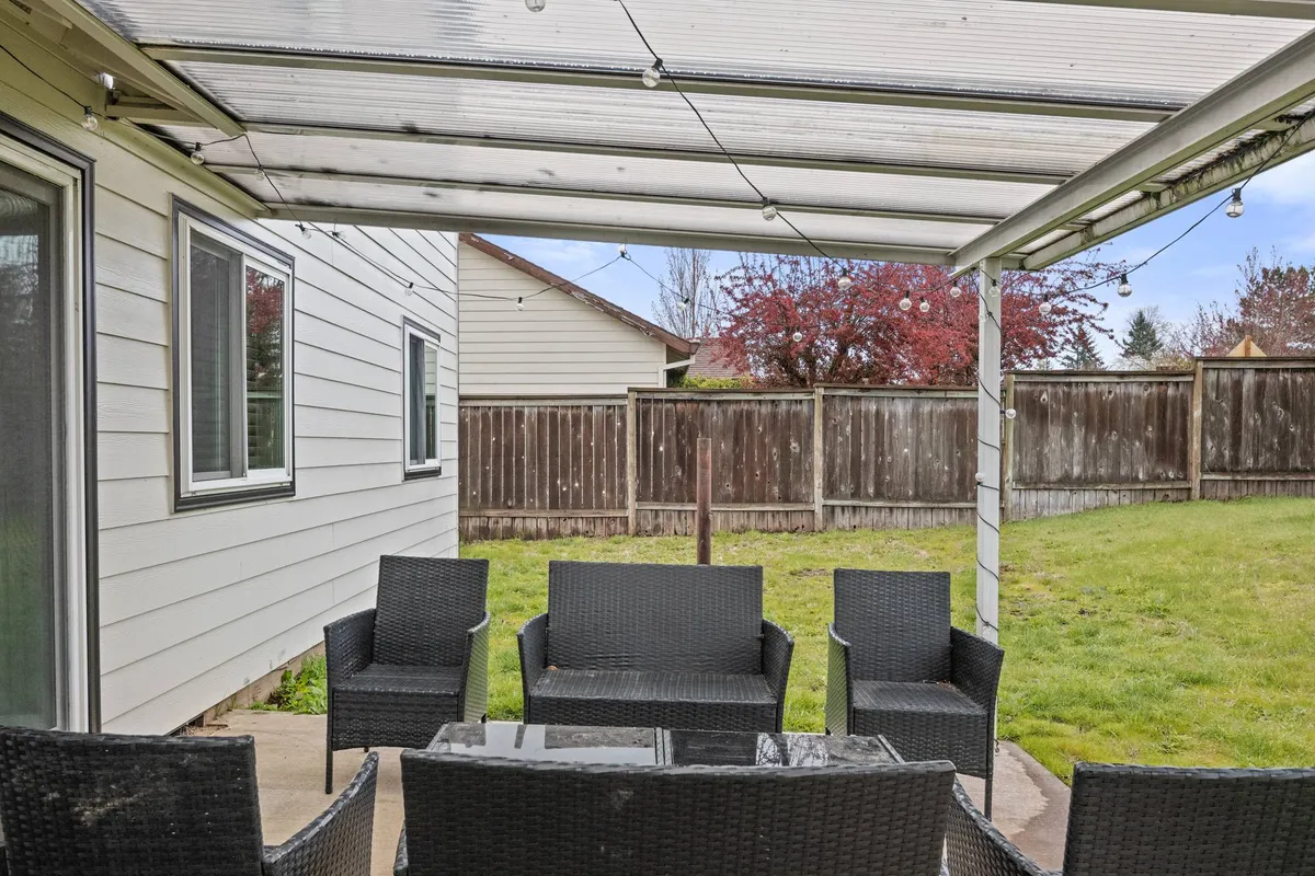 A different angle of the outdoor living space, this photo highlights a cozy seating arrangement under charming string lights. The scene is set for family barbecues, casual gatherings, and relaxed evenings, reinforcing the idea of tranquil outdoor living.