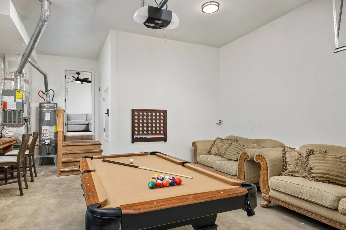 This image features a vibrant game room with a pool table as the central focus, surrounded by comfortable couches and a dining table. The atmosphere is inviting and lively, ideal for group gatherings and friendly competition.